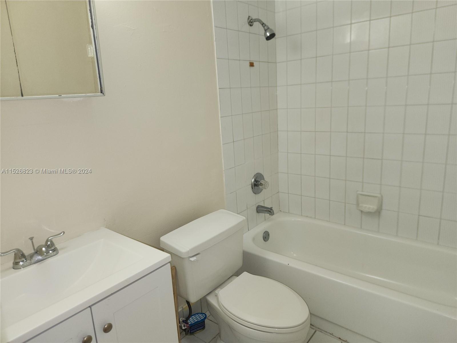6259 West 24th Avenue, Unit 1028 Hialeah, FL 33016 - Photo 12 of 22 a white toilet and a bath tub sitting next to a white sink