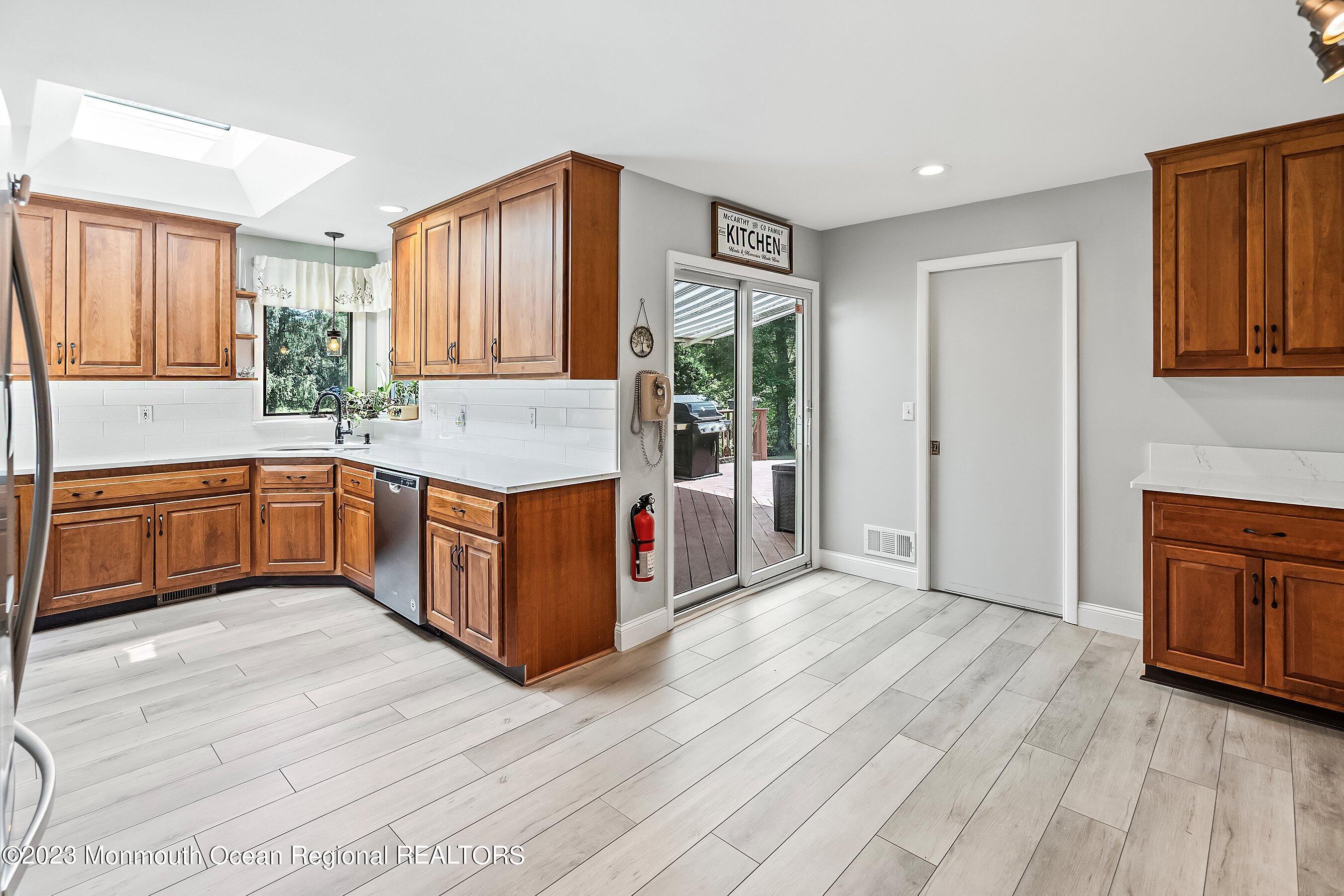 146 Peskin Road Farmingdale, NJ 07727 - Photo 11 of 31 a open kitchen with stainless steel appliances granite countertop a refrigerator a sink dishwasher and wooden cabinets with wooden floor