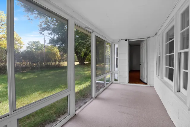 an empty room with chandelier fan and windows