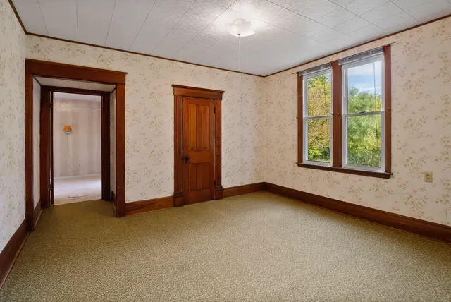an empty room with wooden floor chandelier fan and windows