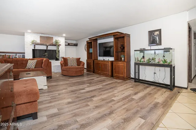a living room with furniture a flat screen tv and a refrigerator