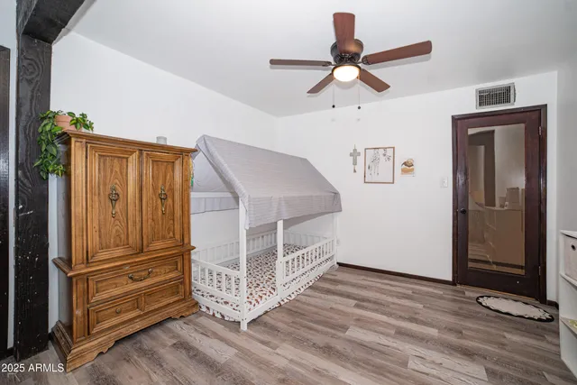 a view of a livingroom with wooden floor a ceiling fan and windows