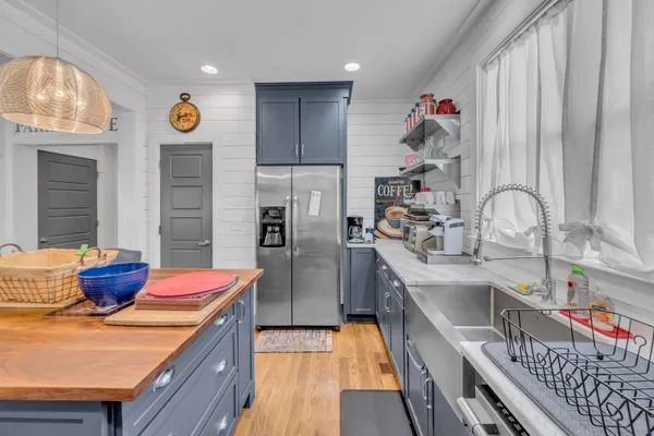 a kitchen with stainless steel appliances granite countertop a sink dishwasher and a refrigerator with wooden floor