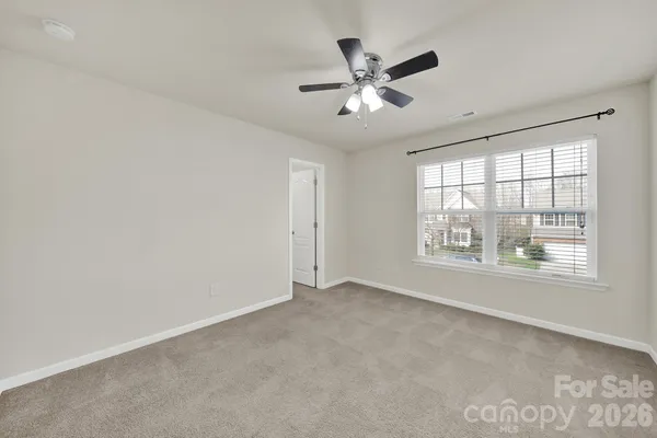 an empty room with chandelier fan and windows