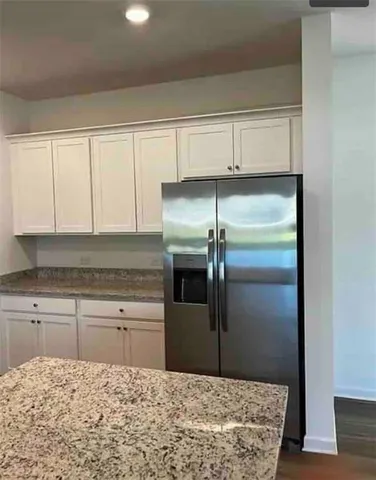 a kitchen with granite countertop a refrigerator and cabinets