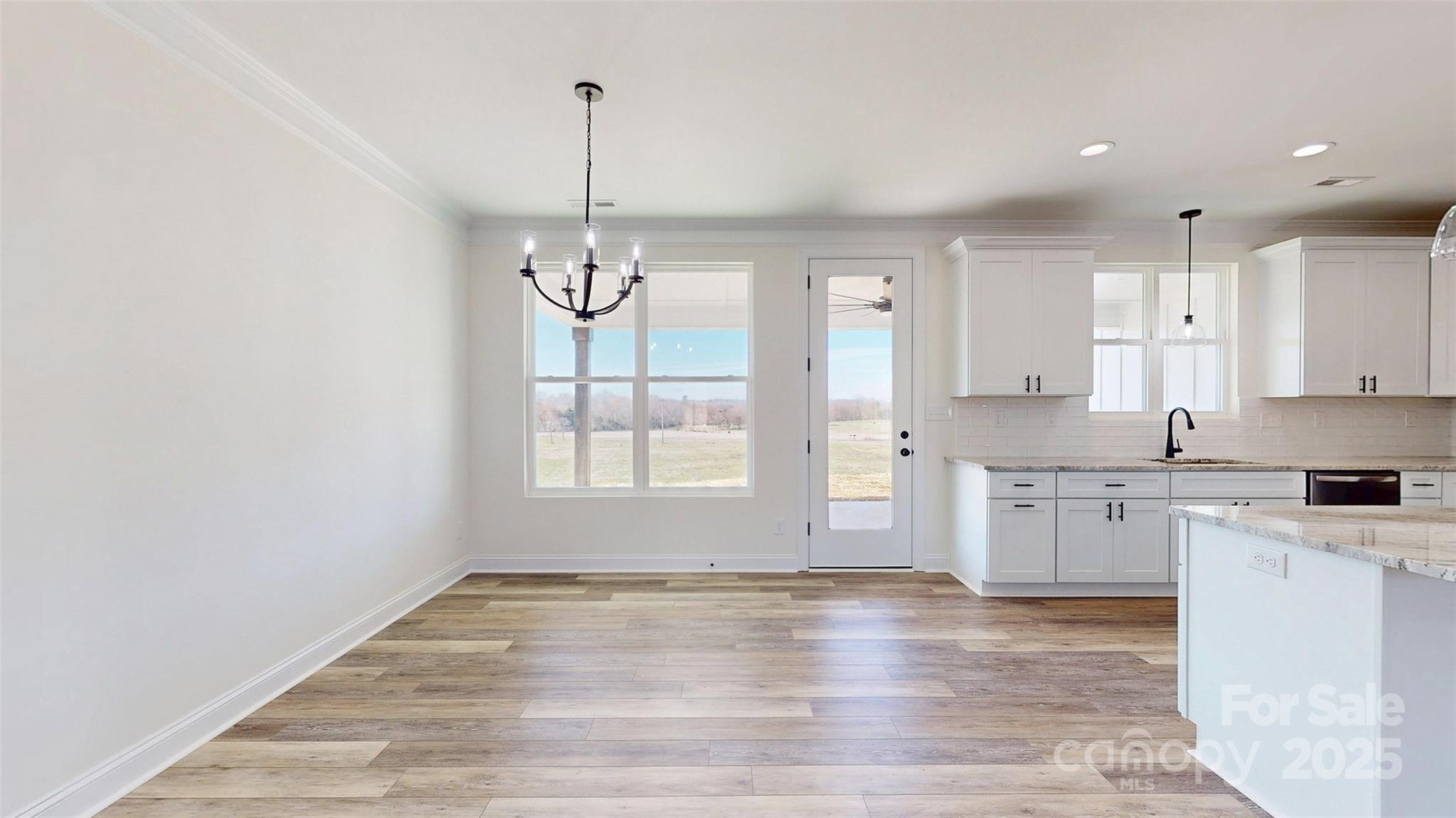 2906 Lathan Road Monroe, NC 28112 - Photo 27 of 41 a large kitchen with granite countertop a stove a sink a window and white cabinets