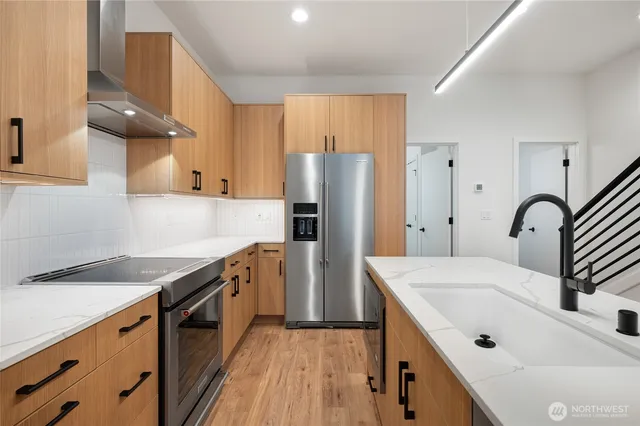 a kitchen with stainless steel appliances granite countertop a sink a stove a refrigerator and cabinets with wooden floor