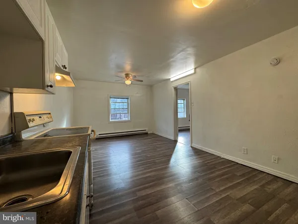 a view of a kitchen with a sink and a stove top oven with wooden floor