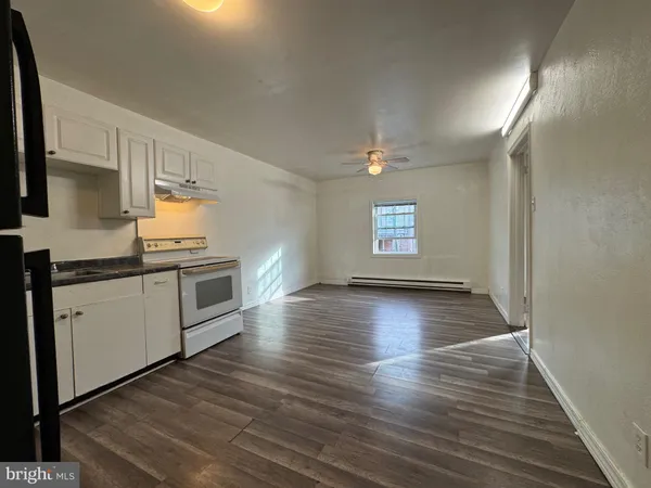 a kitchen with stainless steel appliances granite countertop a stove a sink and white cabinets with wooden floor
