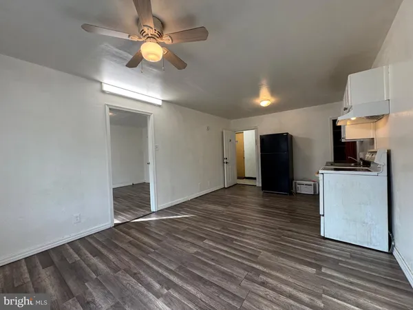 a view of an empty room with kitchen and a window