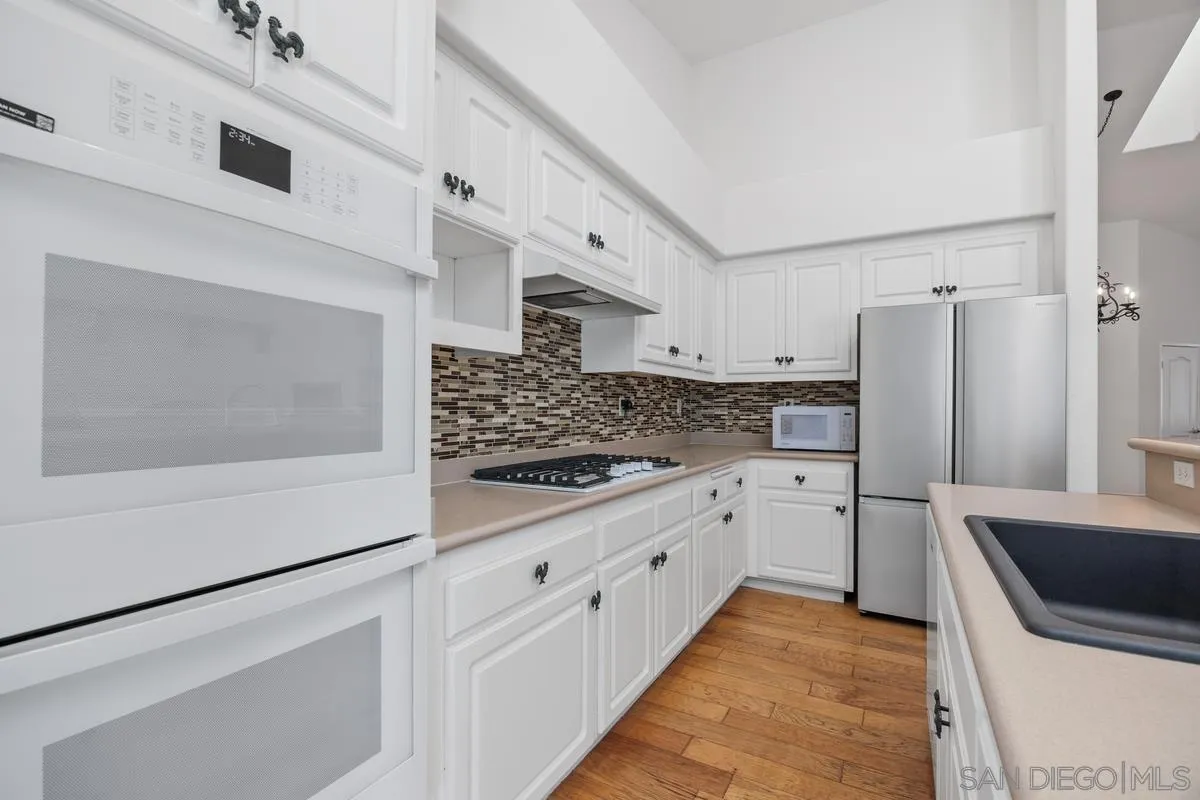 3643 Merced Drive Oceanside, CA 92056 - Photo 9 of 27 a kitchen with white cabinets and stainless steel appliances