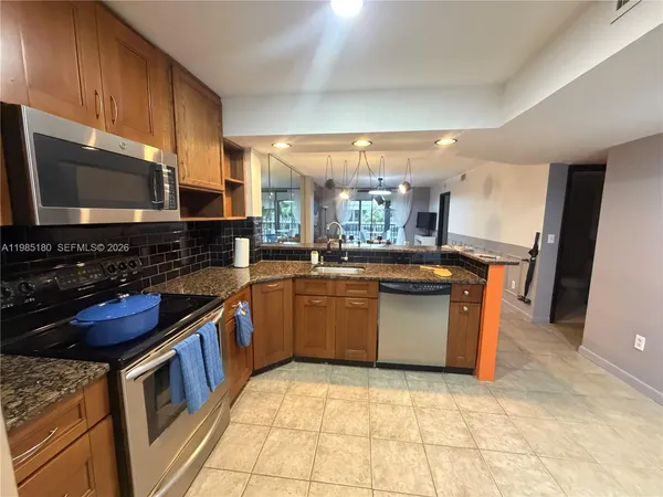 a kitchen with stainless steel appliances granite countertop a stove a sink and a microwave