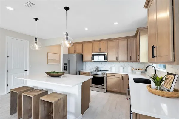 a kitchen with stainless steel appliances kitchen island granite countertop a sink and a large window