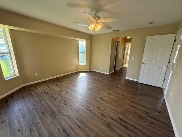a view of an empty room with wooden floor and a window