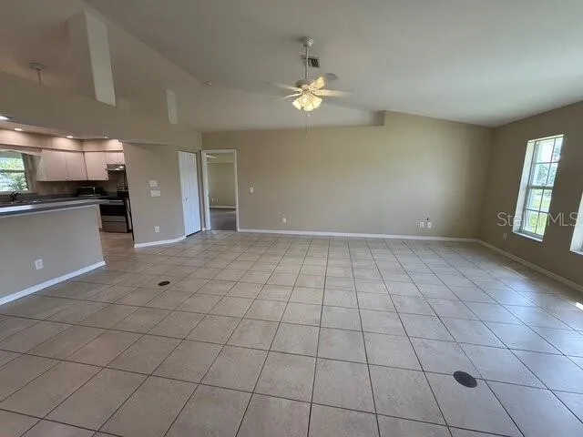 a view of an empty room and a kitchen