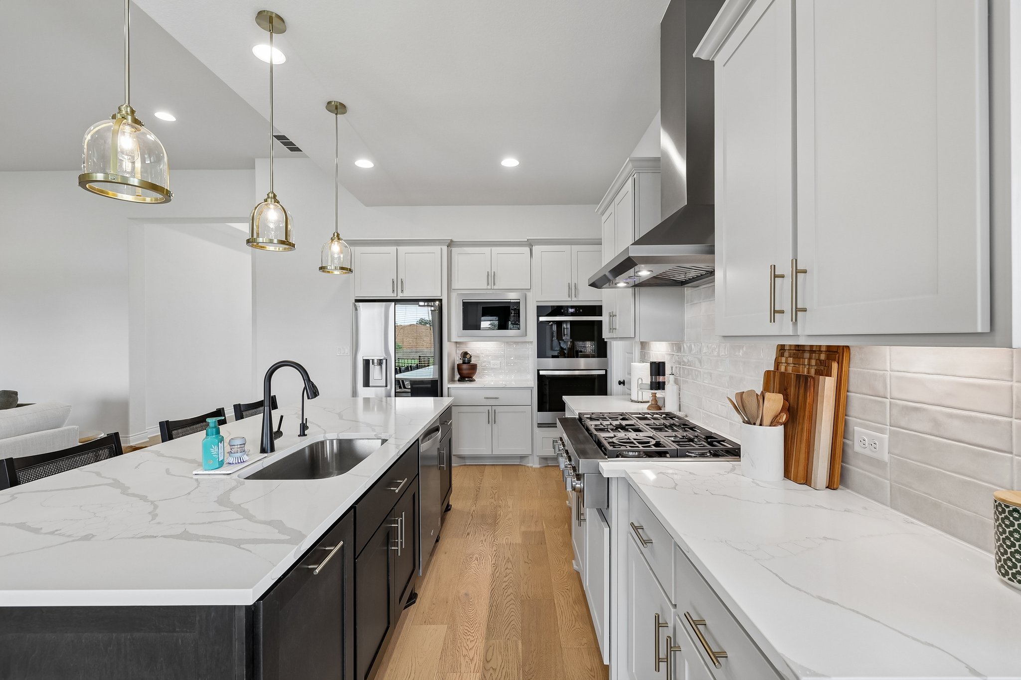 130 Firethorn Loop Bastrop, TX 78602 - Photo 12 of 38 Gourmet kitchen featuring a large island with sink, white countertops, light wood-finish flooring, stainless steel appliances, and pendant lighting
