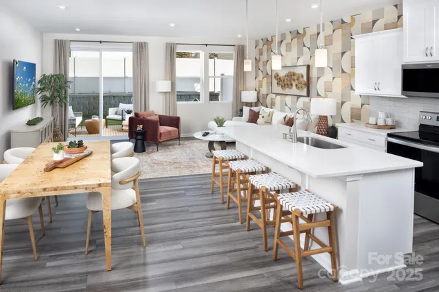 a living room with couches a coffee table and a flat screen tv with kitchen view