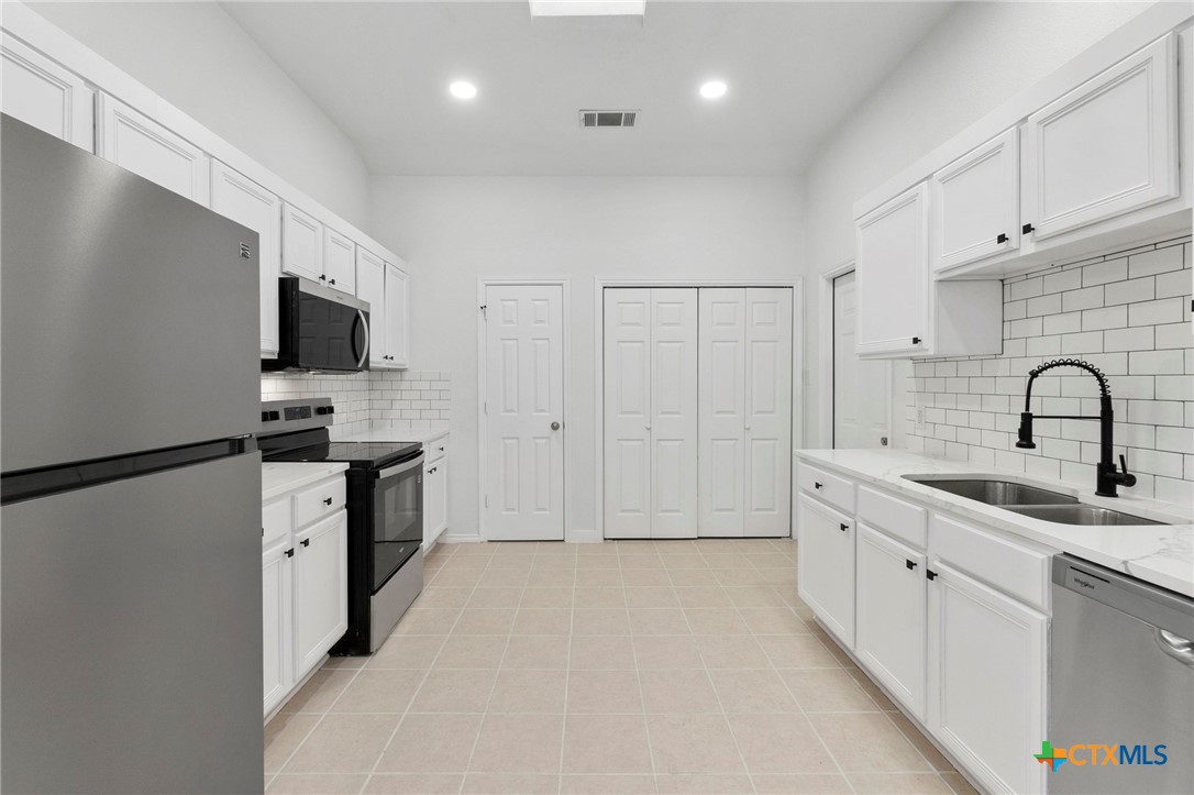 1751 Joy Spring New Braunfels, TX 78130 - Photo 14 of 35 a kitchen with stainless steel appliances a refrigerator sink and white cabinets