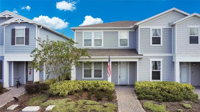 a view of a brick house with large windows and a large tree