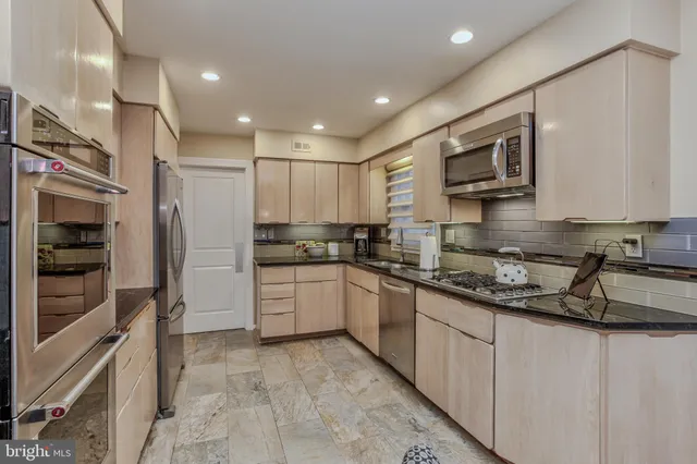 a kitchen with stainless steel appliances granite countertop a refrigerator and a stove top oven