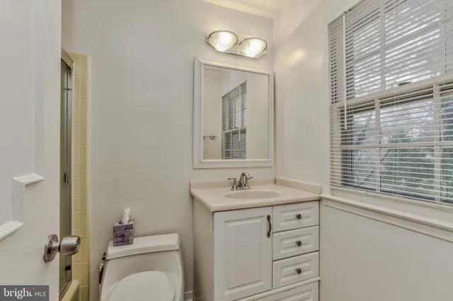 a bathroom with a toilet sink vanity granite and mirror