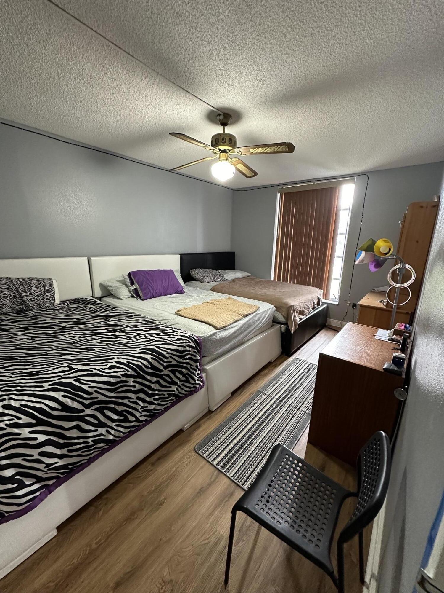 8341 Sands Point Boulevard, Unit B206 Tamarac, FL 33321 - Photo 7 of 11 a bedroom with two beds and a chandelier
