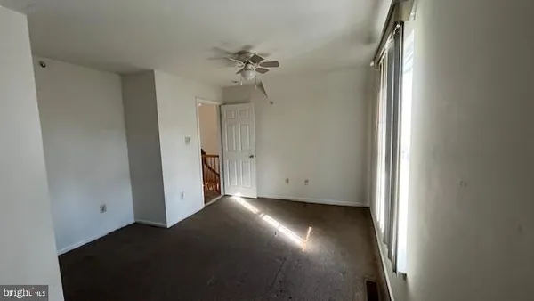 an empty room with chandelier fan and windows
