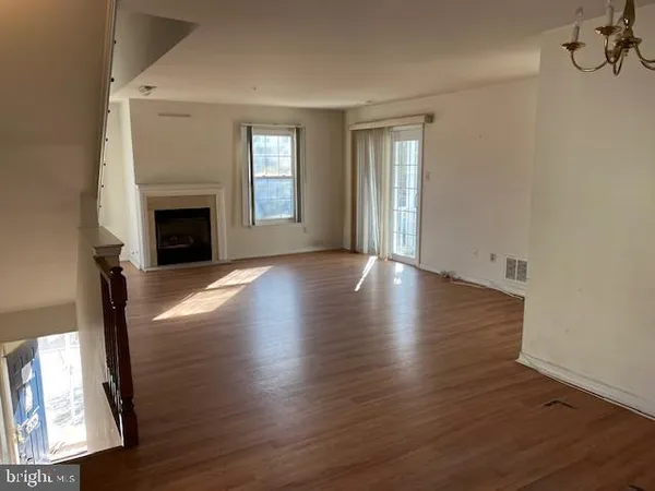 an empty room with wooden floor fireplace and windows