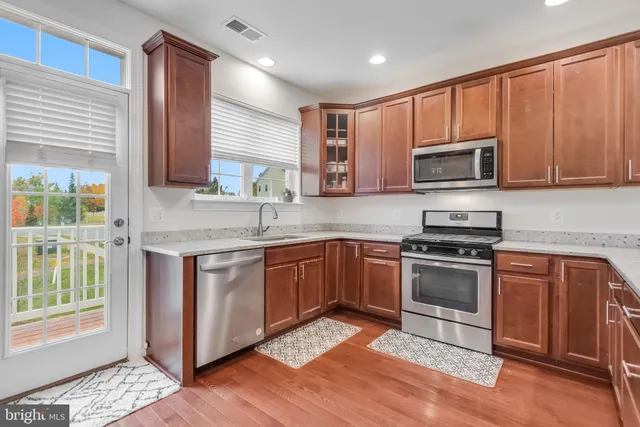 a kitchen with stainless steel appliances granite countertop a stove a sink dishwasher a microwave oven and a refrigerator with wooden cabinets