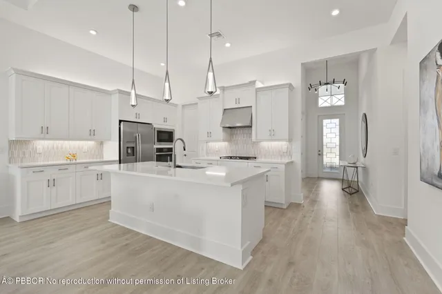 a large kitchen with white cabinets and stainless steel appliances