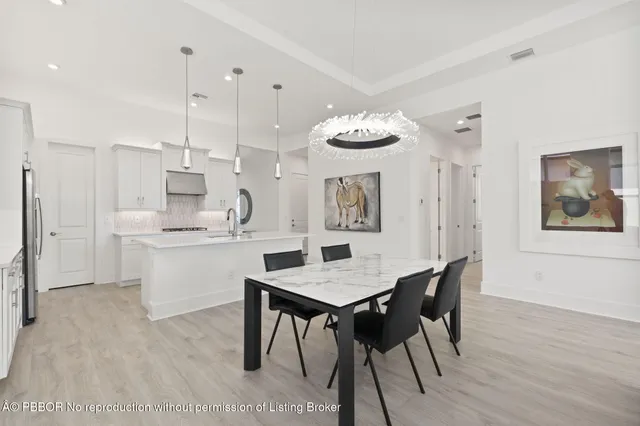 a kitchen with stainless steel appliances kitchen island a table chairs and a refrigerator