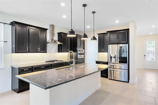 a kitchen with stainless steel appliances granite countertop a refrigerator a sink a stove and oven