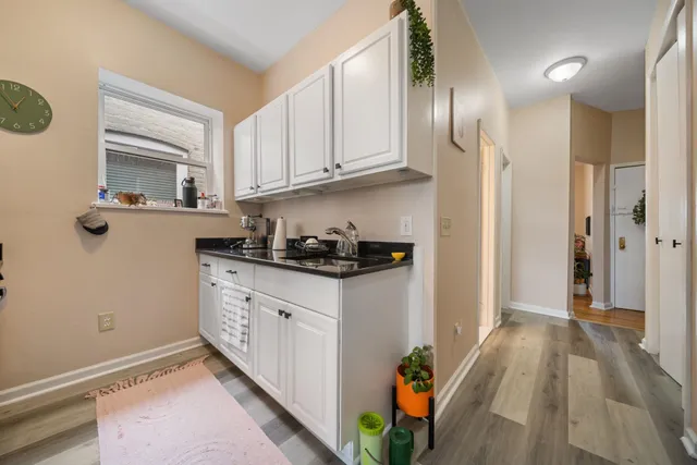 a kitchen with stainless steel appliances granite countertop a refrigerator a sink dishwasher and white cabinets with wooden floor