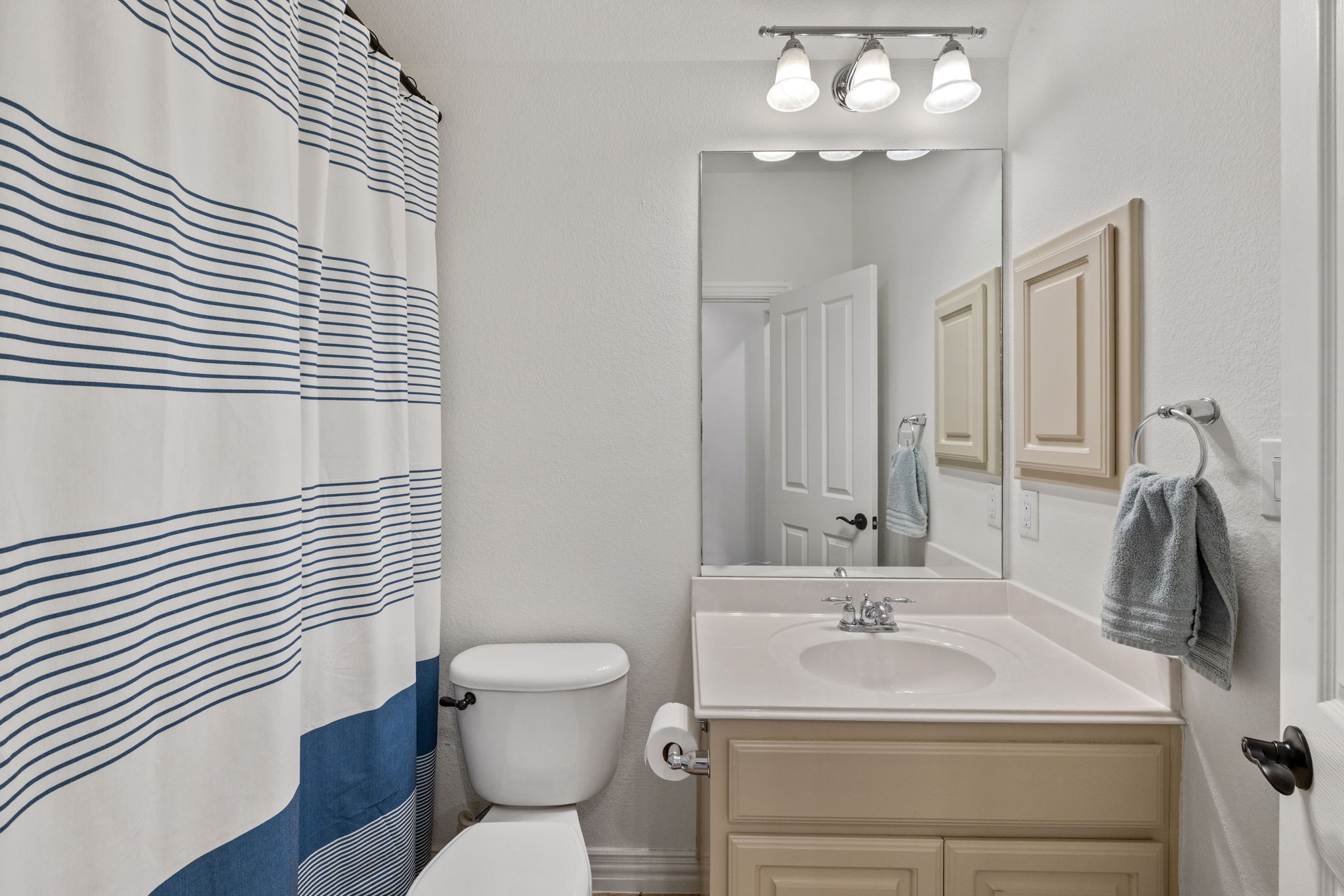 1124 Castle Path Round Rock, TX 78681 - Photo 29 of 40 A clean, functional bathroom features a single vanity, a toilet, and a shower with a striped curtain.