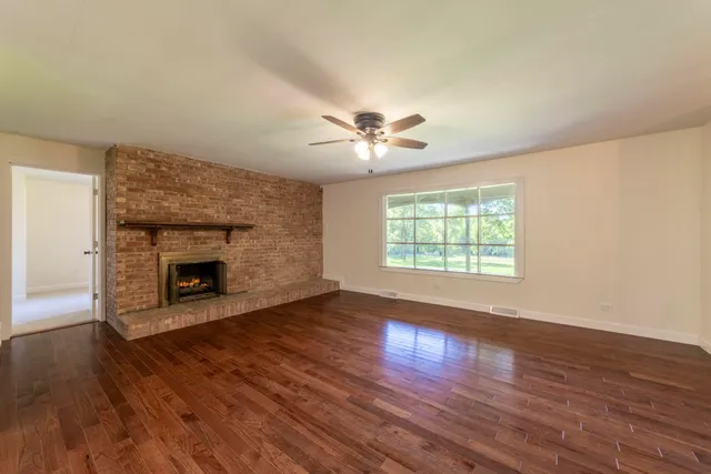 a living room with stainless steel appliances wooden floor and a fireplace