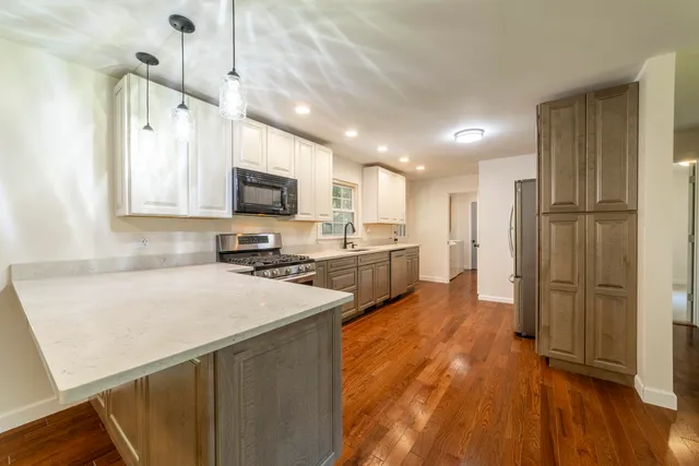 a kitchen with stainless steel appliances sink a stove and a refrigerator with wooden floor