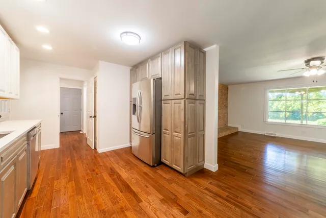 a view of empty room with wooden floor and fan