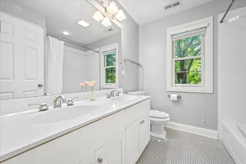 a bathroom with a double vanity sink toilet and a mirror