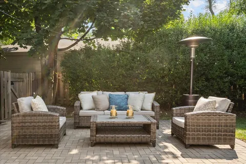 a view of backyard with couches table and chairs and wooden fence