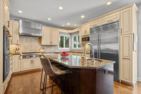 a kitchen with kitchen island granite countertop a sink cabinets and stainless steel appliances