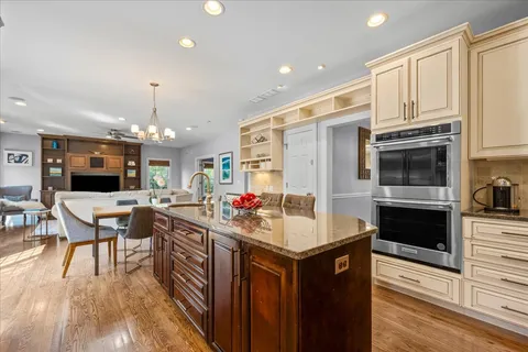 a kitchen with stainless steel appliances a stove top oven a sink dishwasher and a refrigerator with wooden floor