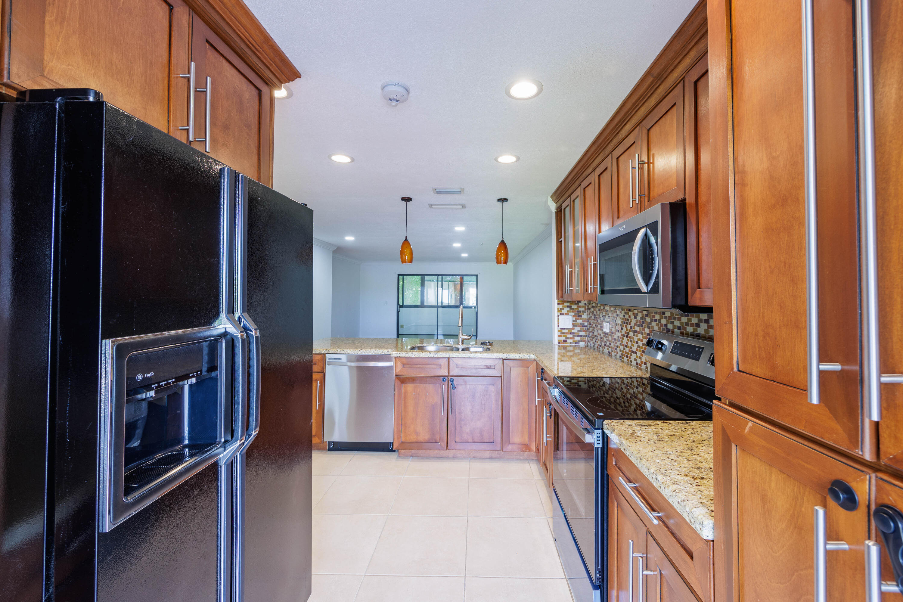 a large kitchen with stainless steel appliances kitchen island granite countertop a refrigerator and a stove top oven