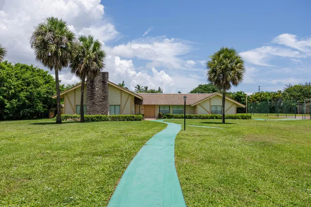 a view of a house with a big yard and palm trees