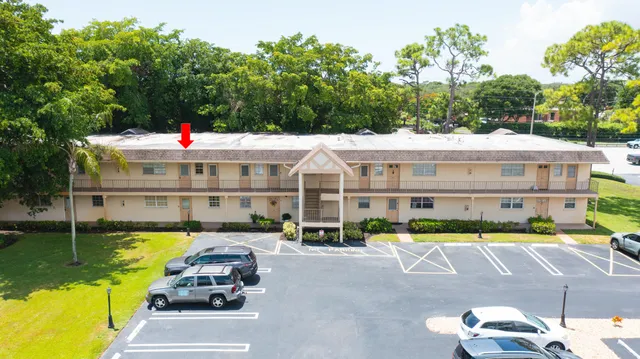 a view of a white building with swimming pool and lawn chairs under an umbrella