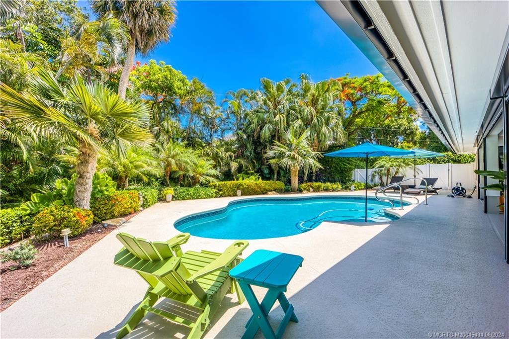 121 Hillcrest Drive Stuart, FL 34996 - Photo 18 of 65 a view of a swimming pool with a table and chairs under an umbrella