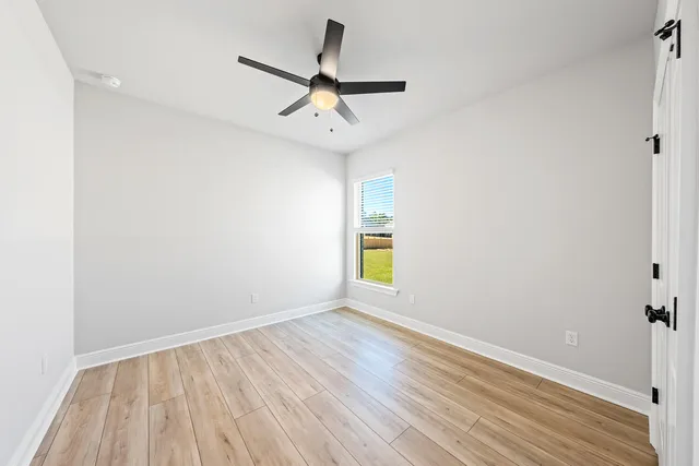 an empty room with a window and ceiling fan