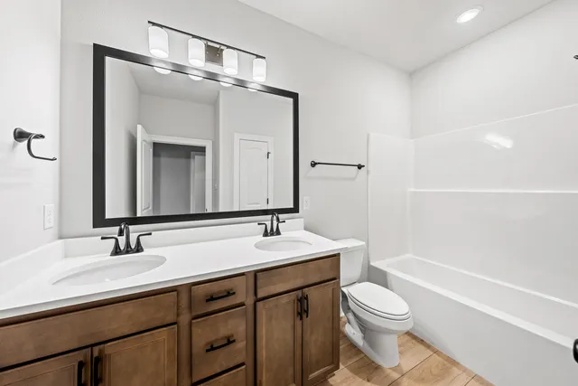 a bathroom with a toilet a sink a mirror a bathtub and vanity