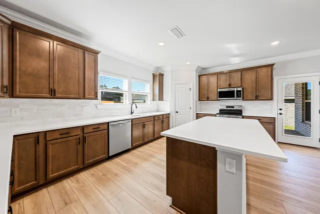 a large kitchen with stainless steel appliances kitchen island granite countertop a sink dishwasher a stove top oven a refrigerator with island and cabinets