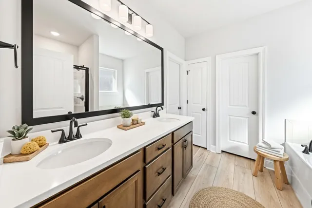 a spacious bathroom with a double vanity sink a mirror and a shower