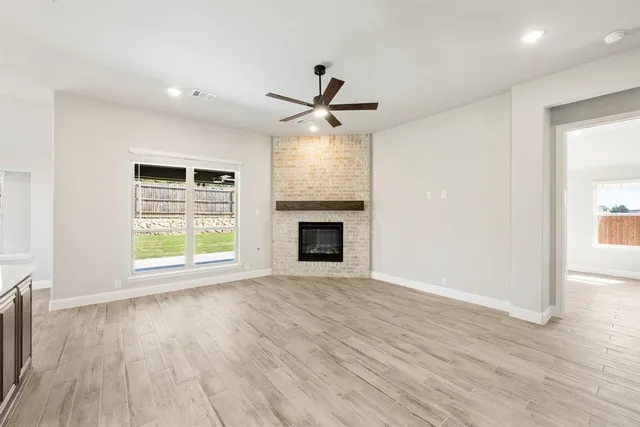 an empty room with wooden floor fireplace and windows